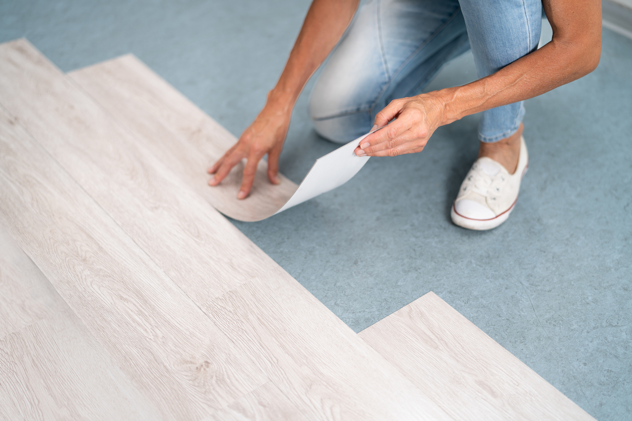a person laying luxury vinyl on a bedroom floor