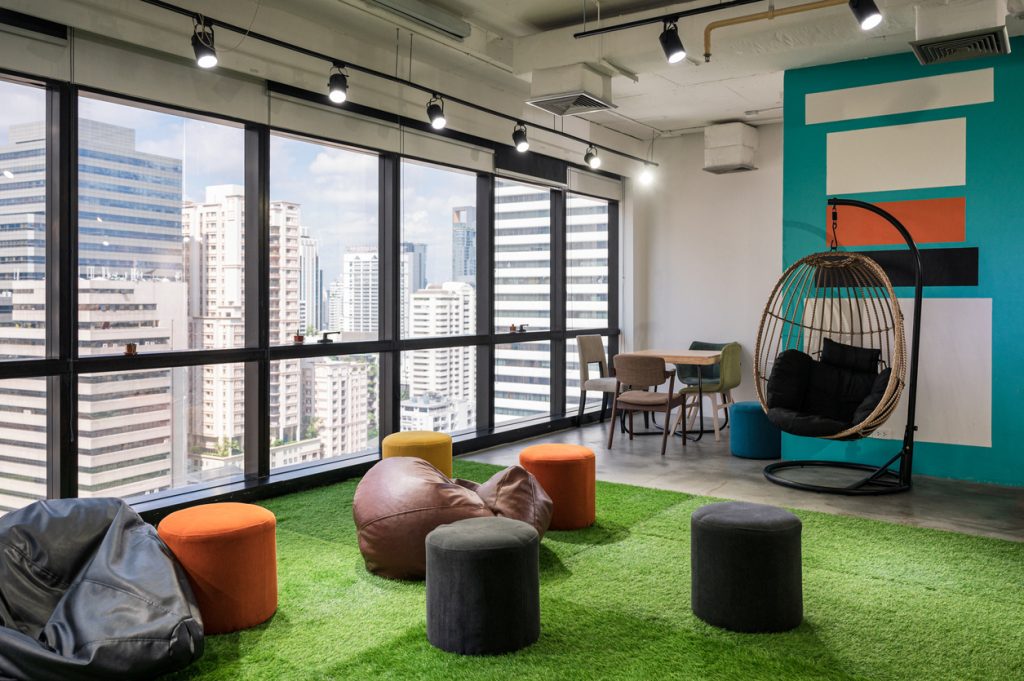 Creative room coworking space with cushions and chairs on artificial grass in manchester office